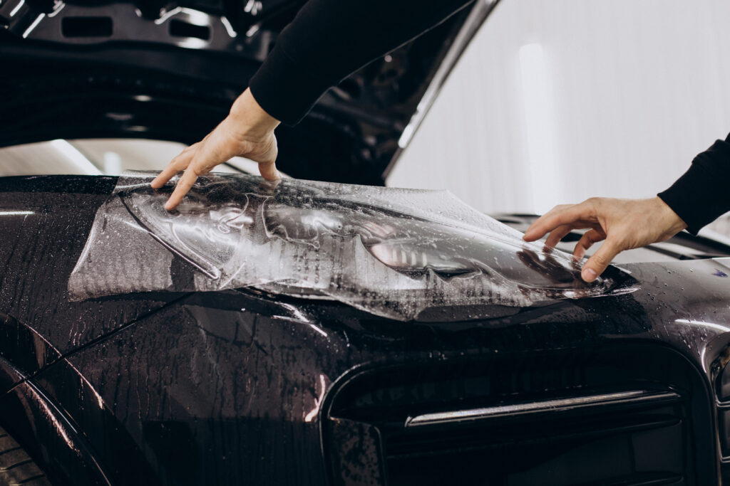 Male worker wrapping car with ptotective foil